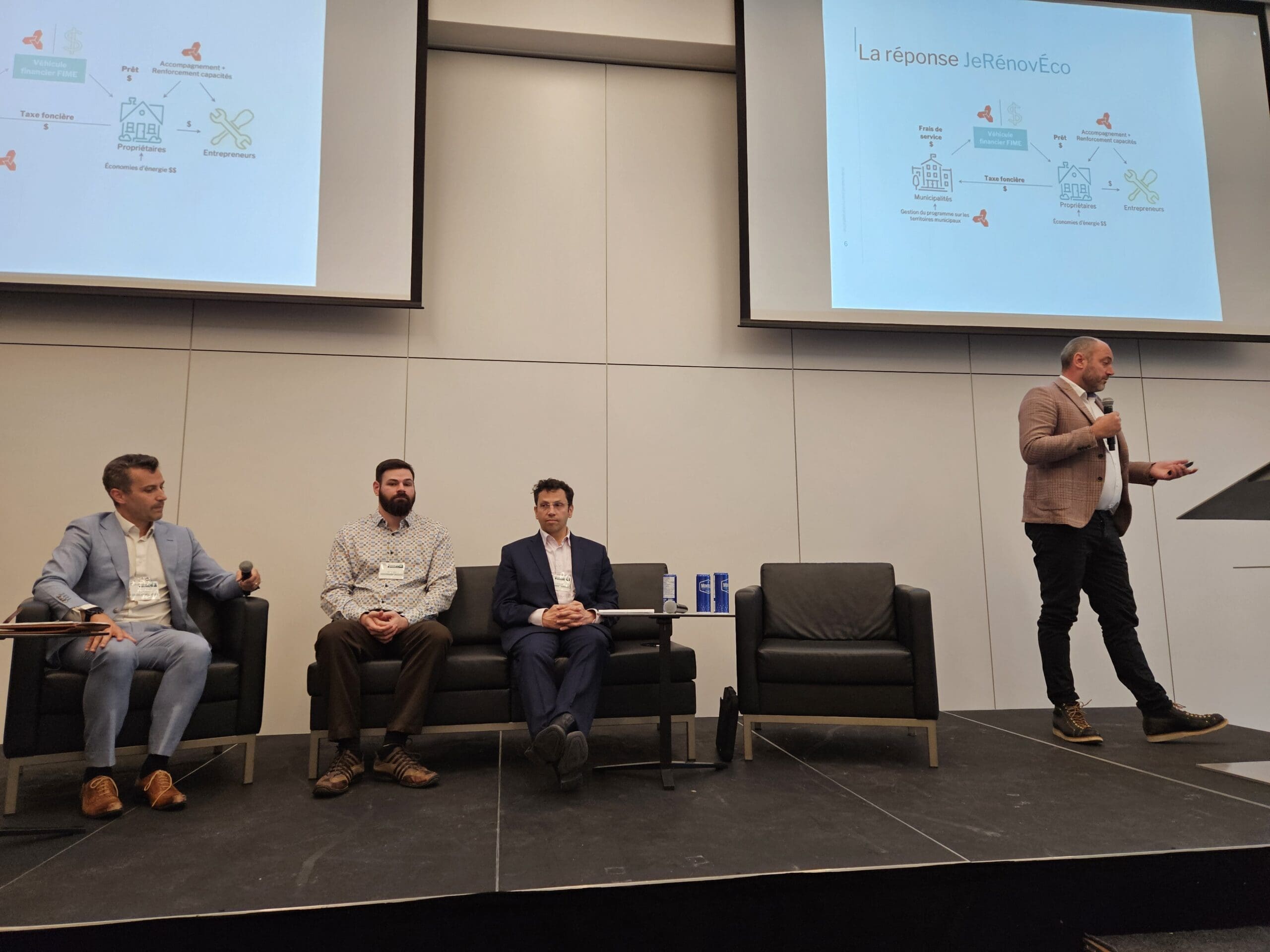 "Un homme se tient sur un podium et s'adresse à un public lors d'un événement organisé par Nature Québec. Trois hommes sont assis sur la scène