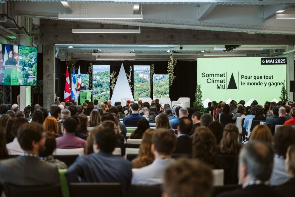 Photo du panel d'ouverture du Sommet Climat Montréal 2025. Du monde est assis face à la scène principale où est inscrit "Pour que tout le monde y gagne."