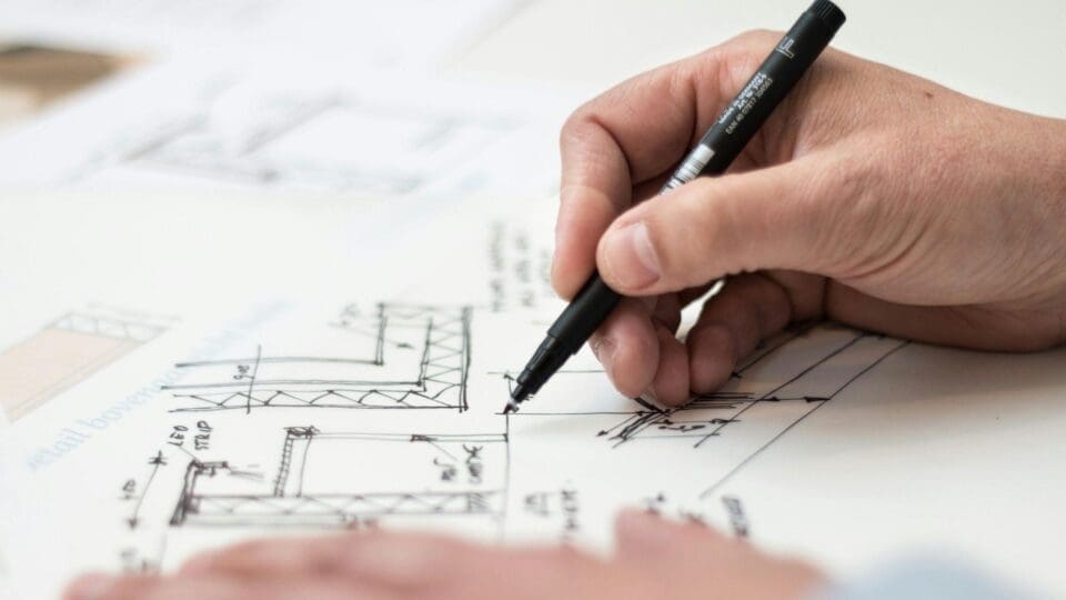 Une main tient un stylo et annote le plan d'un appartement