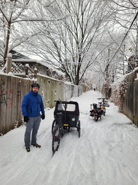 Homme dans une ruelle enneigé de Montréal avec des vélos Locomotion