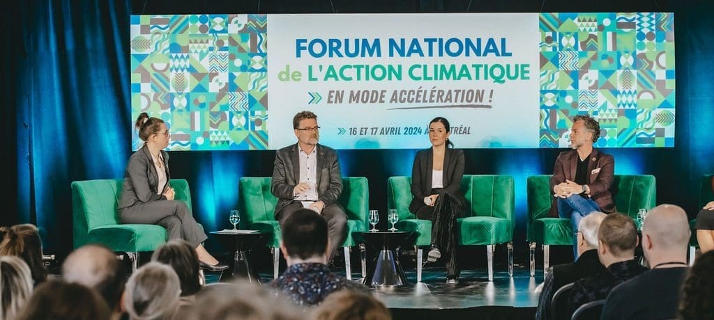 Quatre personnes sont assises sur la scène et participent à un panel au Forum national de l'action climatique à Montréal. L'auditoire regarde attentivement la toile de fond vibrante de l'événement FNAC2024 de la RNCREQ, qui met en évidence les discussions clés et les détails de l'événement.