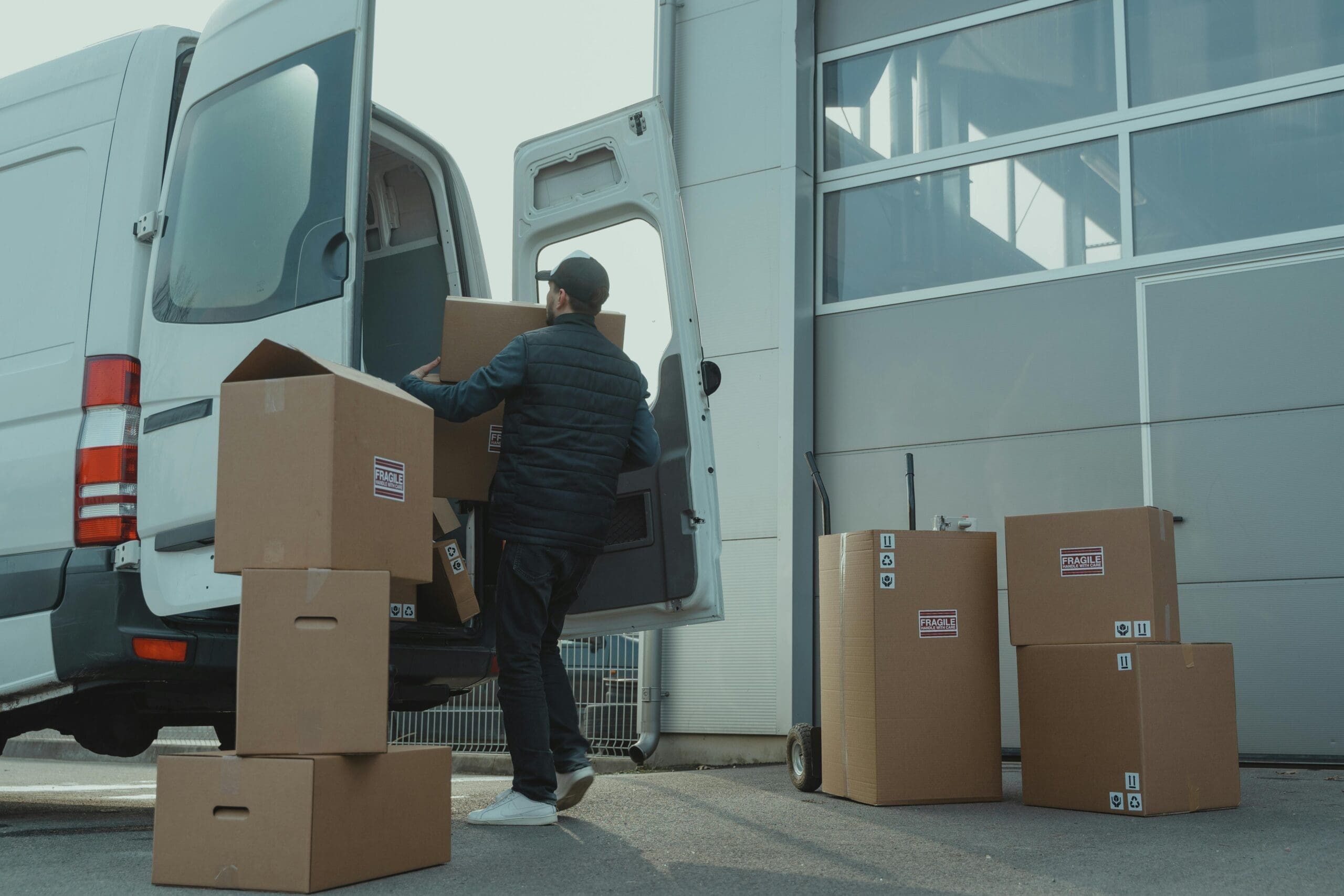 Homme qui charge de boîtes de cartons dans une véhicule blanc