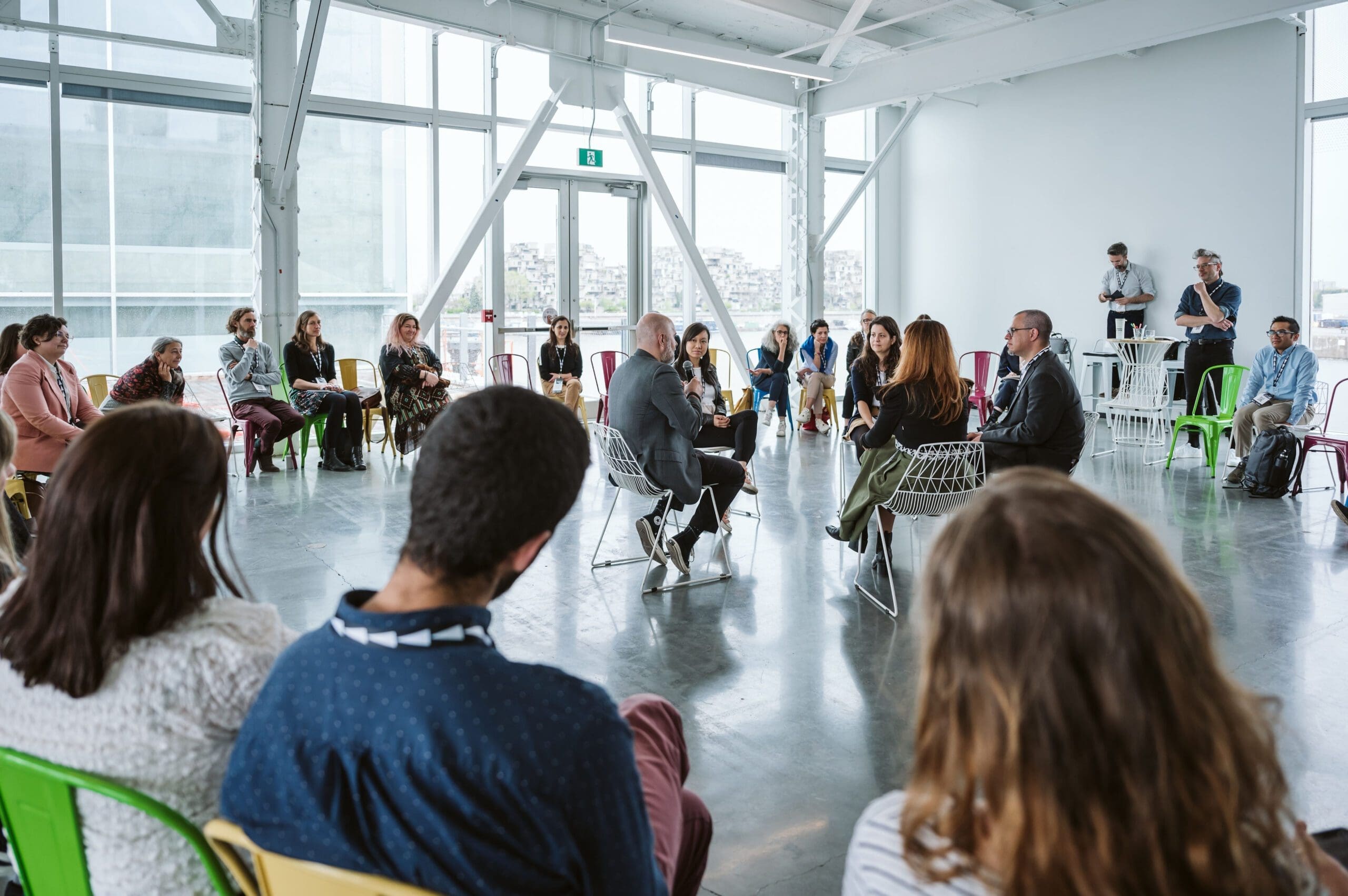 Cinq personnes sont assises en cercle sur des chaises et discutent au Sommet Climat 2024, entourées d'un public mixte.