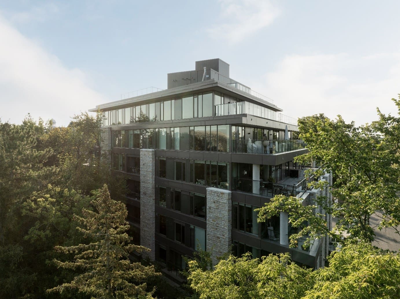 Les résidences modernes à étages Stone Abbey à Ottawa sont dotées de grandes baies vitrées et d'un design épuré. Elles sont nichées au milieu des arbres dans une zone boisée sereine où la lumière du soleil s'infiltre délicatement à travers les branches.