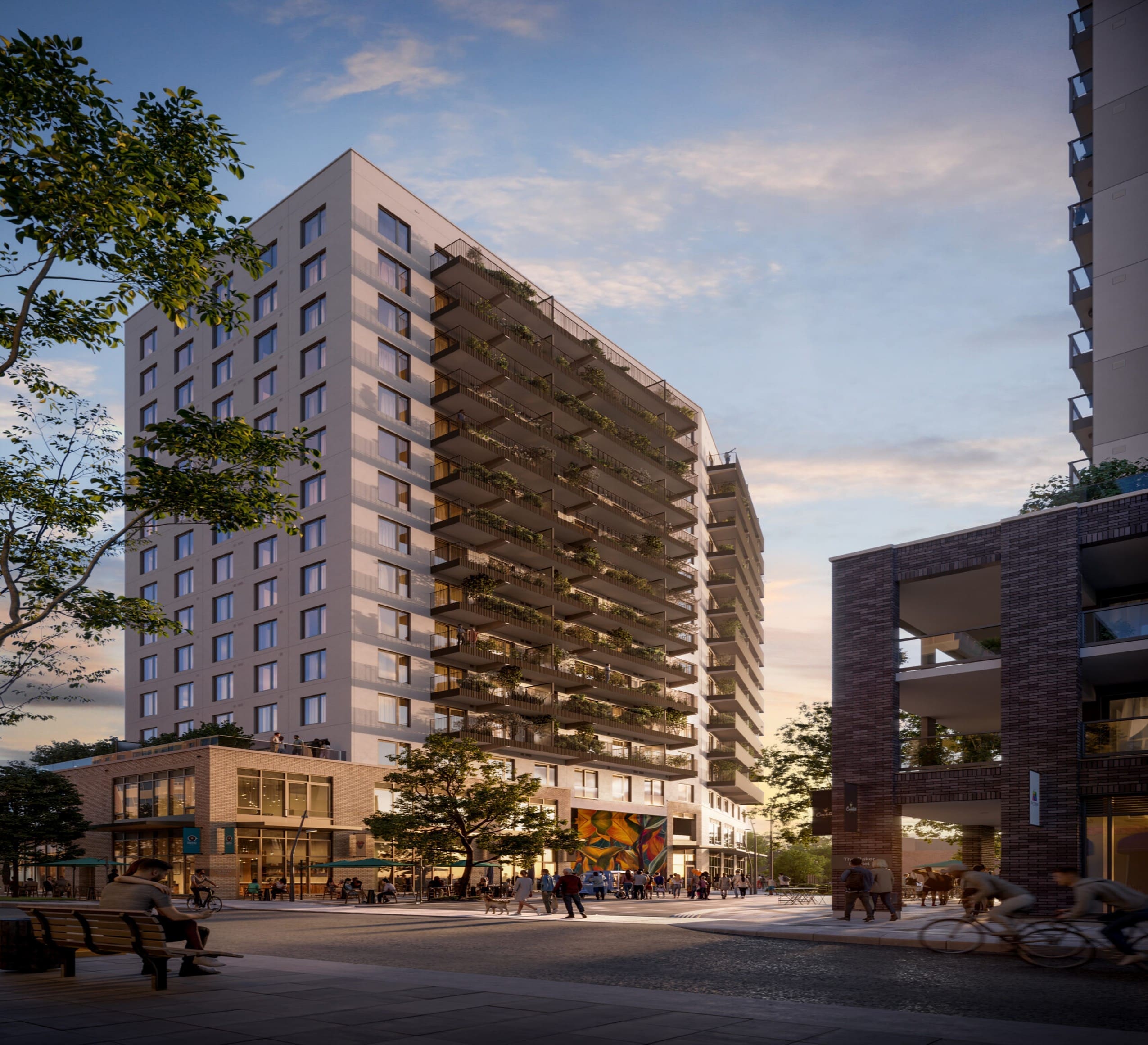 Au coucher du soleil, les appartements du Baker District à Guelph se dressent, hauts et modernes, avec de grands balcons et une fresque murale vibrante au niveau du sol. Les gens se promènent à pied ou à vélo le long de la rue, entourés d'arbres luxuriants et des bâtiments voisins.