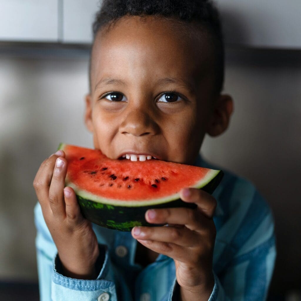Un jeune garçon croque dans un melon d'eau